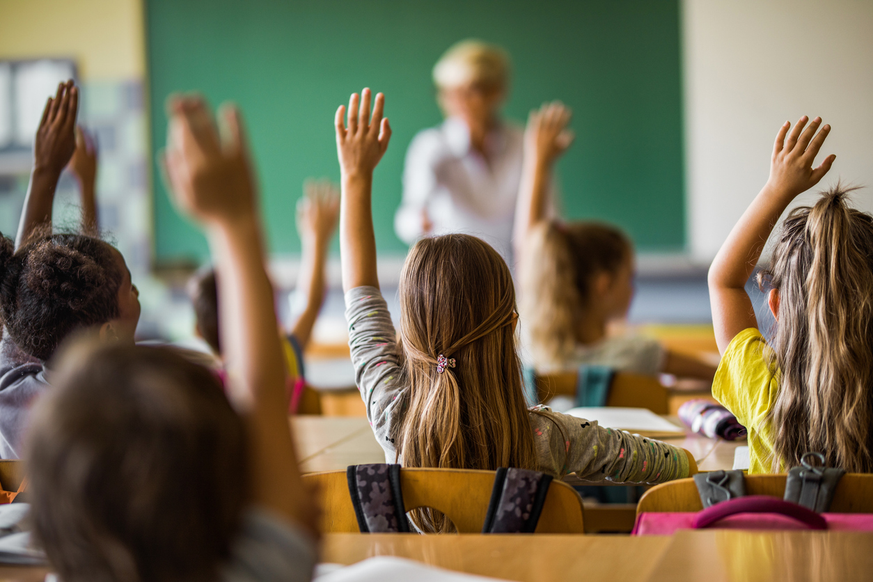 Kids raising hands in school